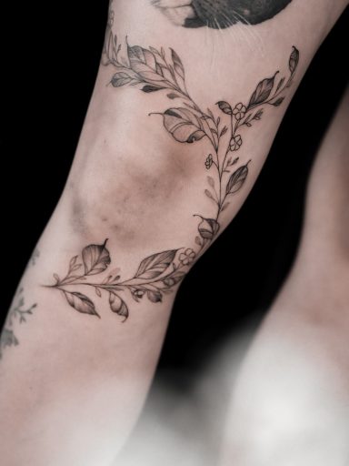 Freehand botanical fineline tattoo, leaves around a knee done in Lörrach by vegan tattoo artist Jannine Stefanov