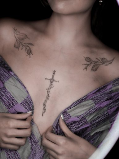 Fineline Sternum sword tattoo and freehand leaves on collarbones, done in Lörrach by vegan tattoo artist Jannine Stefanov
