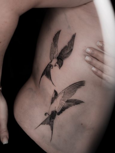 semi-realistic fineline swallow bird tattoo on ribs, done in Lörrach by vegan tattoo artist Jannine Stefanov